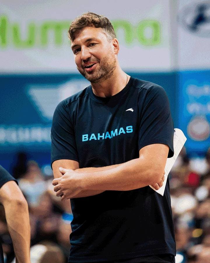 Man in 'Bahamas' shirt smiling at an event.
